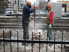 Workers drilling holes for Bustar expansive grout. Workers drilling holes for Bustar expansive grout.